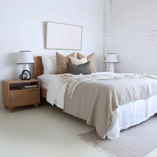 A wooden bed with 4 designer bed cushions in a bright room.