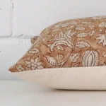 Floral cushion laid horizontally. This perspective shows the edge of the designer fabric and its square shape.