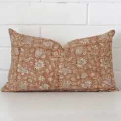 Floral cushion cover sits against a white wall. It is constructed from a superior looking designer material and has rectangle dimensions.
