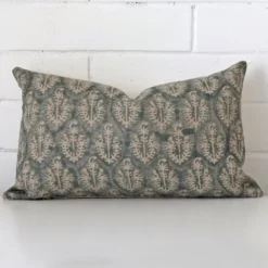 White wall with a cushion laying against it. It has a distinctive designer fabric and has a rectangle shape.