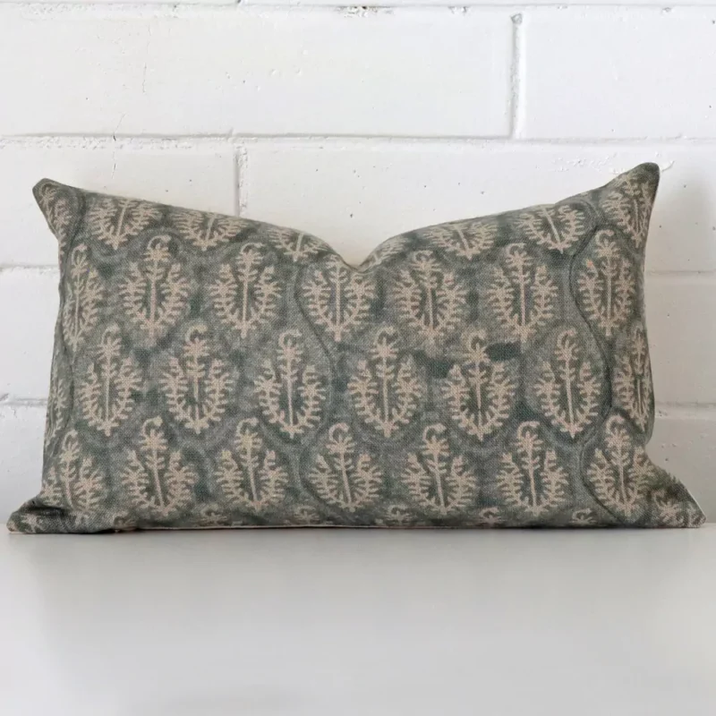 mavis-designer-cushion-cover-rectangle-art127-30 White wall with a cushion laying against it. It has a distinctive designer fabric and has a rectangle shape.