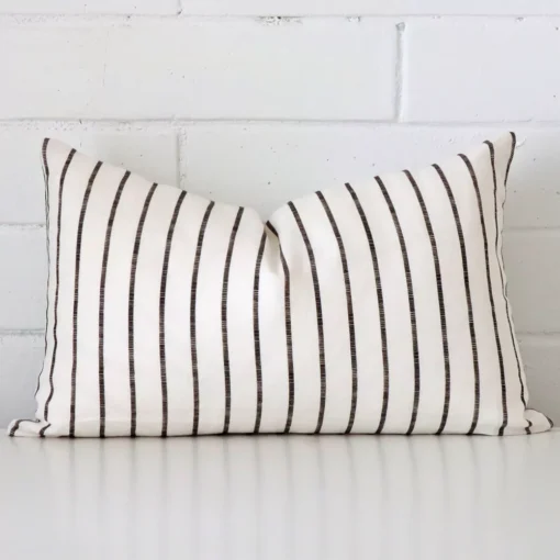 Striped cushion cover in front of a white wall. It has a rectangle size and is made from a linen material.