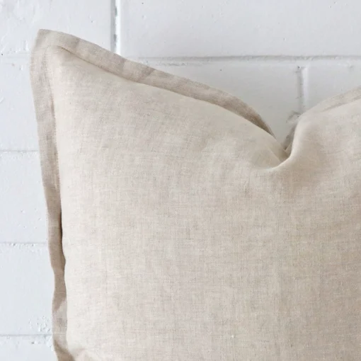 Close up view showing a corner of this linen cushion in a square size and with natural colouring.