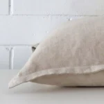The edge of this linen square cushion in natural is shown. The shot shows the front and rear panels.