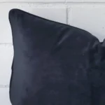 The corner of this navy FABRIC cushion is shown close up. It has a rectangle shape.