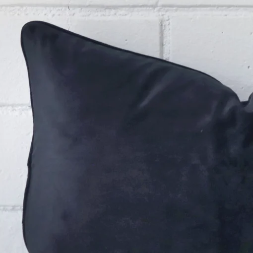 The corner of this navy FABRIC cushion is shown close up. It has a rectangle shape.