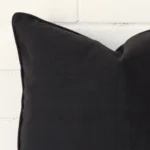 A macro image of the top left corner of this linen cushion. It is possible to see the finer detail of the square shape and black colour.