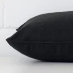 The edge of this linen rectangle cushion in black is shown. The shot shows the front and rear panels.