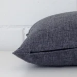 Charcoal cushion cover laid on its back side. The image shows a side-on view of the linen material and its square dimensions.