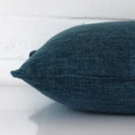 Prussian blue cushion cover laying sideways against brick wall. The square size and linen material are shown highlighting the seams.