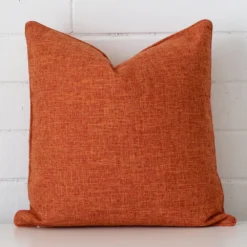 Rust linen cushion cover features prominently against a white wall. It is a square design.