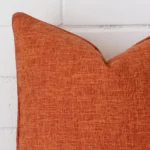 Close range image of rust cushion. The square size and linen material can be seen in detail.