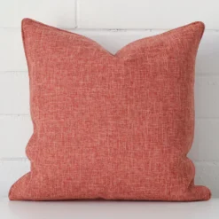 Focused view of square cushion cover. The shot shows details of its linen material and terracotta colour.