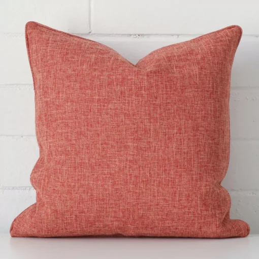 Focused view of square cushion cover. The shot shows details of its linen material and terracotta colour.