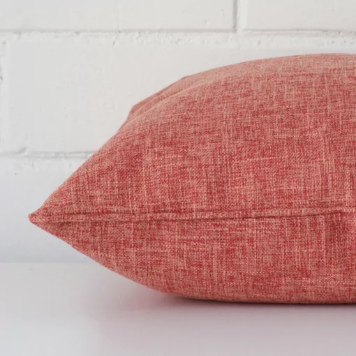 Side edge of square cushion. The linen material and terracotta colour can be seen from this lateral viewpoint.