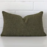 Bold rectangle green cushion positioned in front of white brickwork. It has boucle fabric.