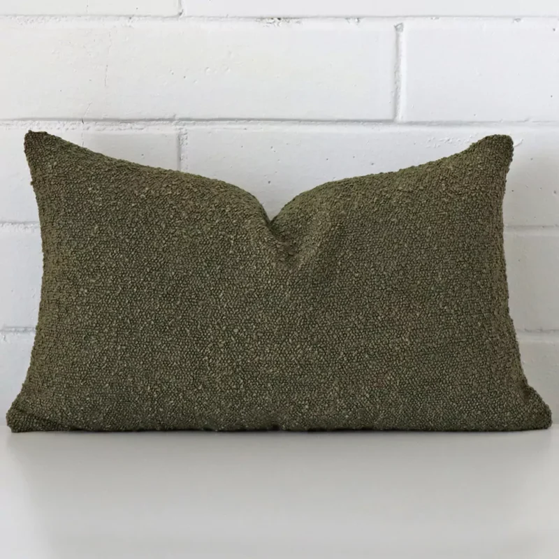 olive-green-boucle-cushion-cover-rectangle-sc1031-30 Bold rectangle green cushion positioned in front of white brickwork. It has boucle fabric.