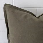 Corner section image showing features of square olive cushion that has linen fabric.