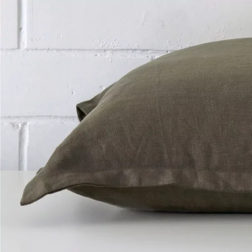 Close side shot of this olive linen cushion cover. The viewpoint shows its square design.