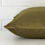 A side view of olive cushion that has velvet fabric and a large size.
