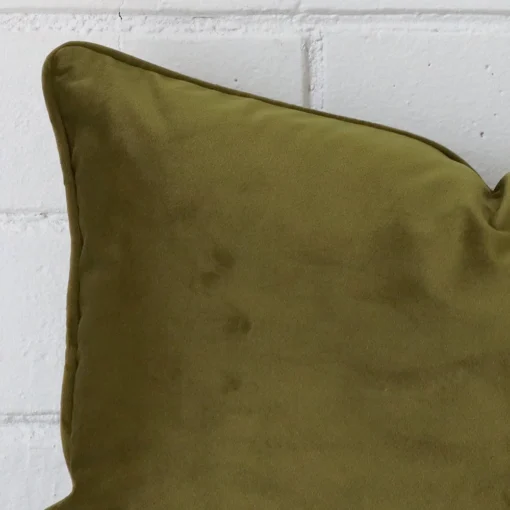 The corner of this velvet rectangle cushion cover is shown close up. Its olive colour is shown in greater detail.