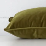 Side angle shot of velvet square cushion cover. The olive hue is shown beautifully.