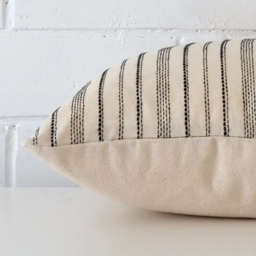 The edge of this designer square cushion is shown. The shot shows the striped design and the front and rear panels.