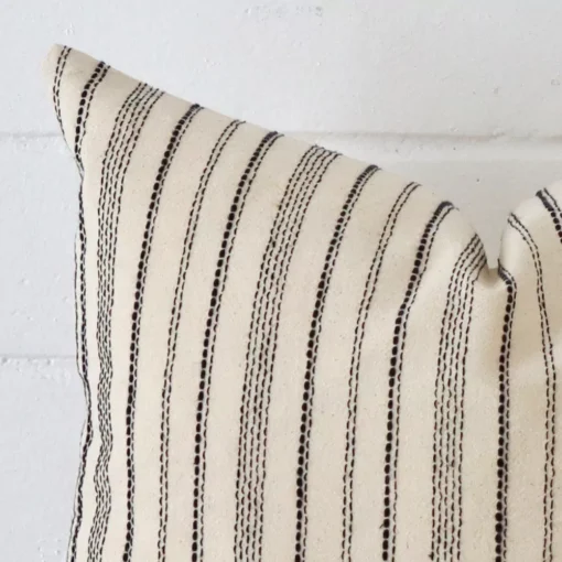 Close range image of striped cushion. The square size and designer material can be seen in detail.