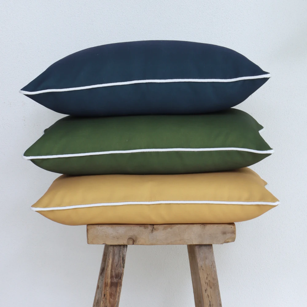 Three outdoor cushions are stacked vertically on a wooden stool.