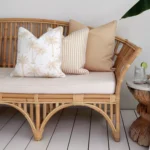 A shot of 3 beige outdoor cushions sitting in a corner of a rattan seat.