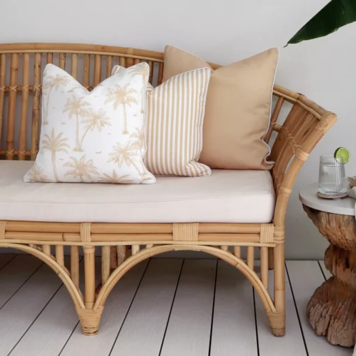 A shot of 3 beige outdoor cushions sitting in a corner of a rattan seat.
