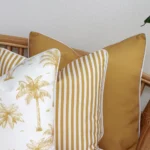 A close-up shot showcases a set of three mustard couch cushions, featuring a solid colour, a stripe, and a palm design.