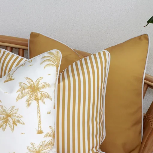 A close-up shot showcases a set of three mustard couch cushions, featuring a solid colour, a stripe, and a palm design.