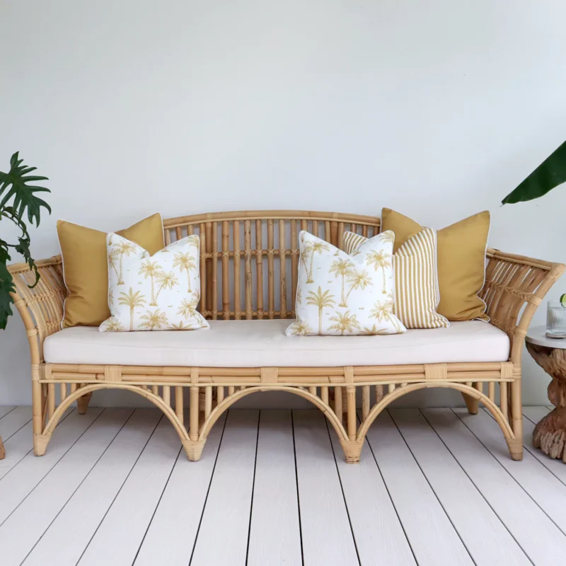 palm-mustard-outdoor-sofa-cushions-set-5-covers-colo1171 A set of five mustard outdoor cushions sits on a rattan seat nestled against a white wall.