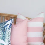 A close-up shot of 3 pink outdoor couch cushions on a corner of a rattan seat.