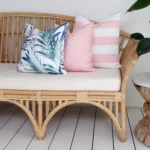 A nice shot capturing the corner of a rattan seat with 3 pink outdoor couch cushions.