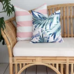 A rattan outdoor seat adorned with pink cushion covers carefully arranged on its corner inviting you to unwind in style.