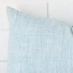 The corner of this linen rectangle cushion cover is shown close up. The duck egg colour is shown in greater detail.