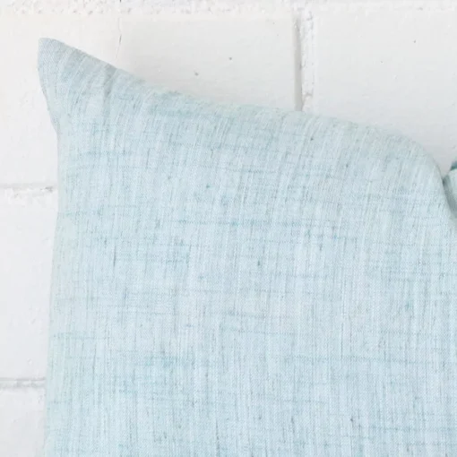 The corner of this linen rectangle cushion cover is shown close up. The duck egg colour is shown in greater detail.