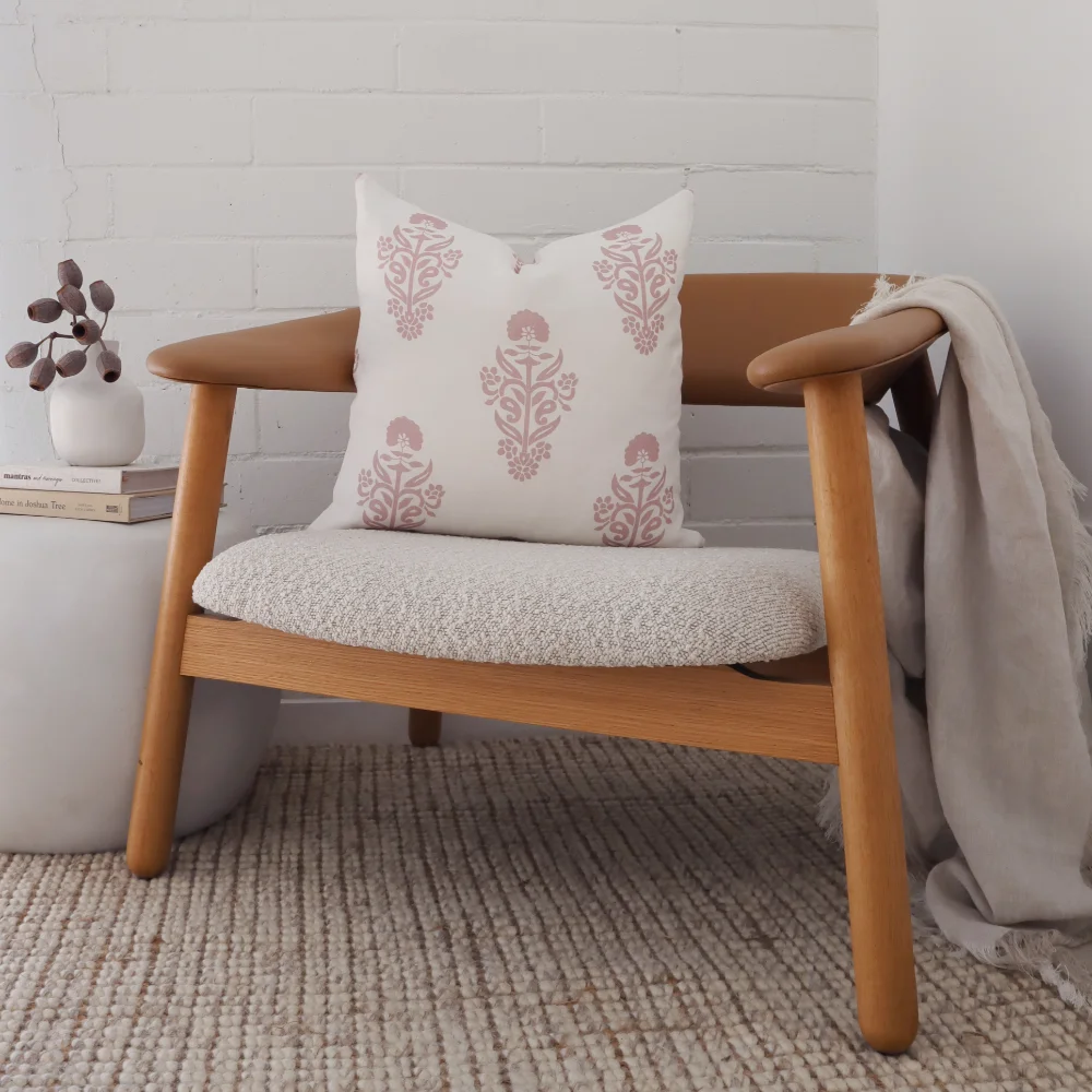 A patterned cushion has been placed on a single chair with a small vase and throw nearby.