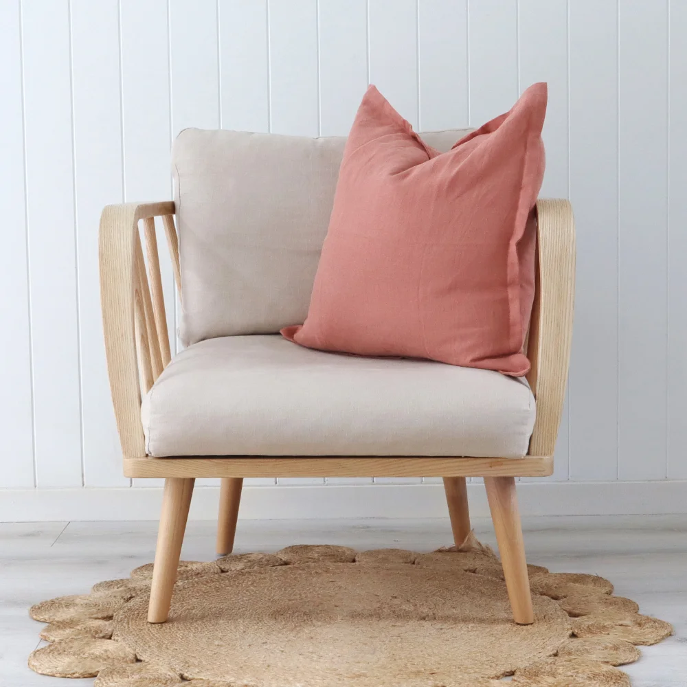 A pink cushion sits angled on a modern seat in a bright room.