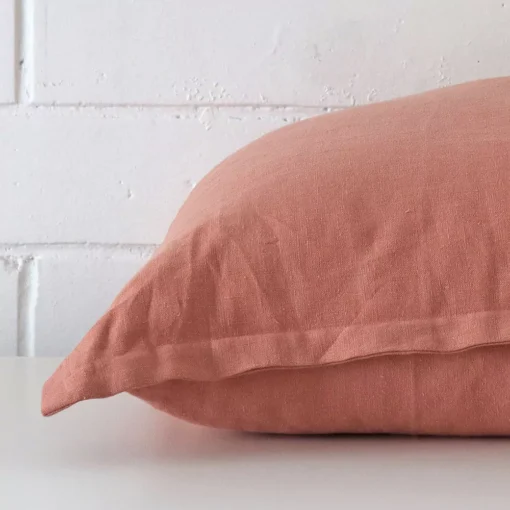 Side angle shot of linen square cushion cover. The pink hue is shown.