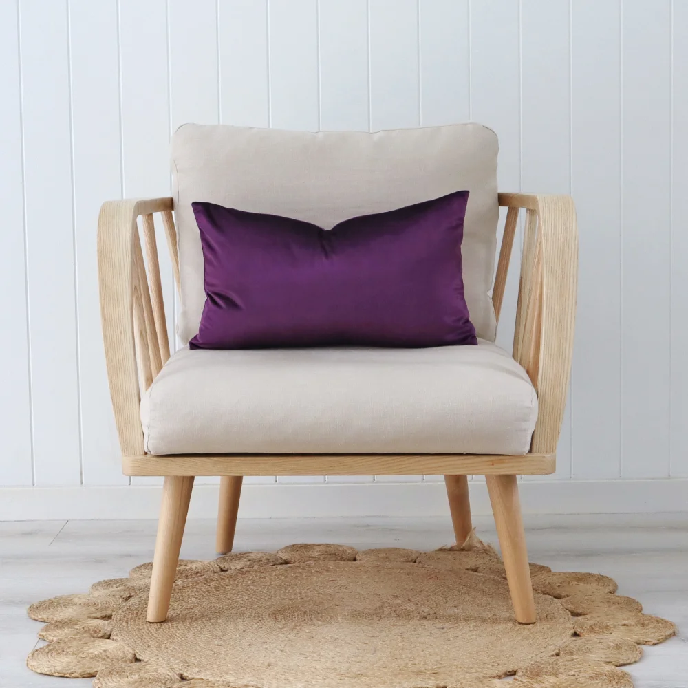 A purple cushion has been styled on a simple wooden chair.