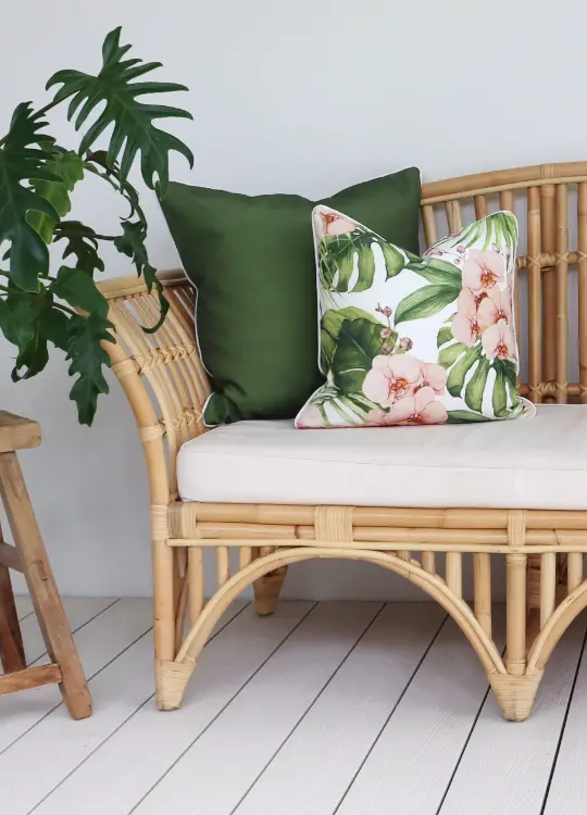 A rattan outdoor seat has two cushion covers on its left side.
