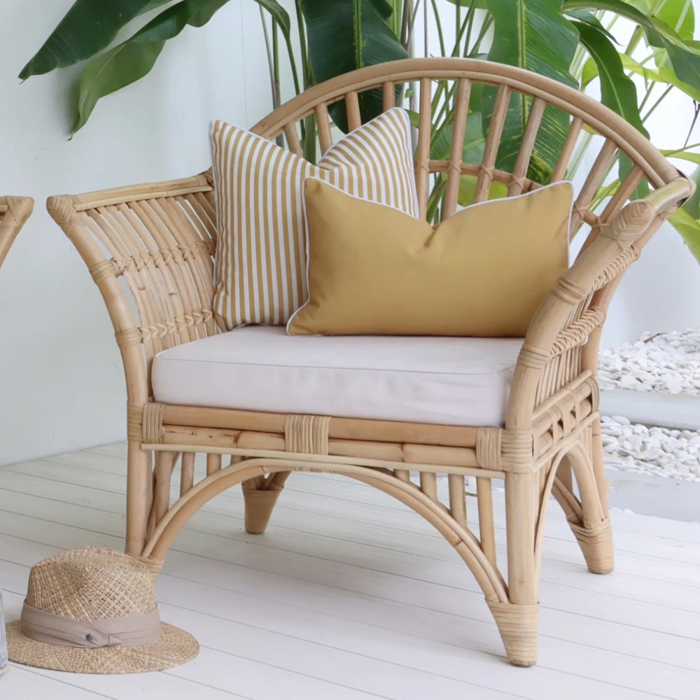 Rectangle outdoor cushions have been styled together on a rattan single chair outside.