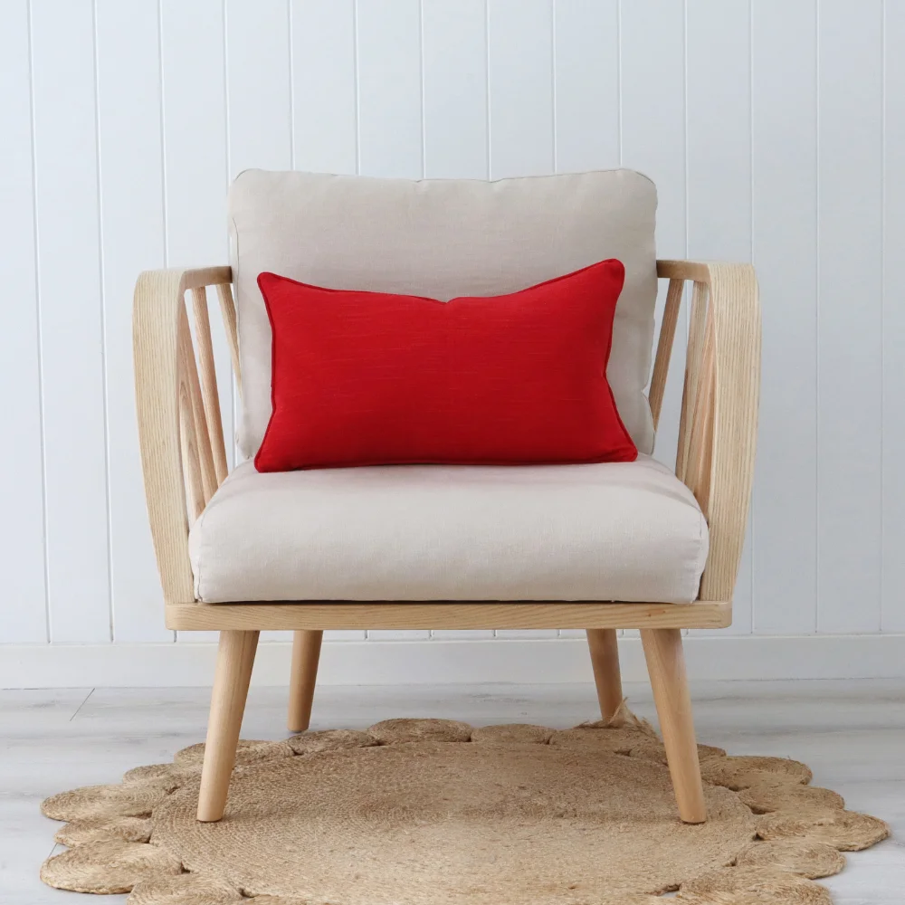 A red cushion is sitting on a modern chair in a bright room.