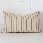 Designer cushion cover features prominently against a white wall. It is a rectangle design and has a striped decorative finish.