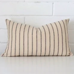 Designer cushion cover features prominently against a white wall. It is a rectangle design and has a striped decorative finish.