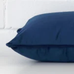 Velvet royal blue cushion laying on its side. It has a rectangle shape.