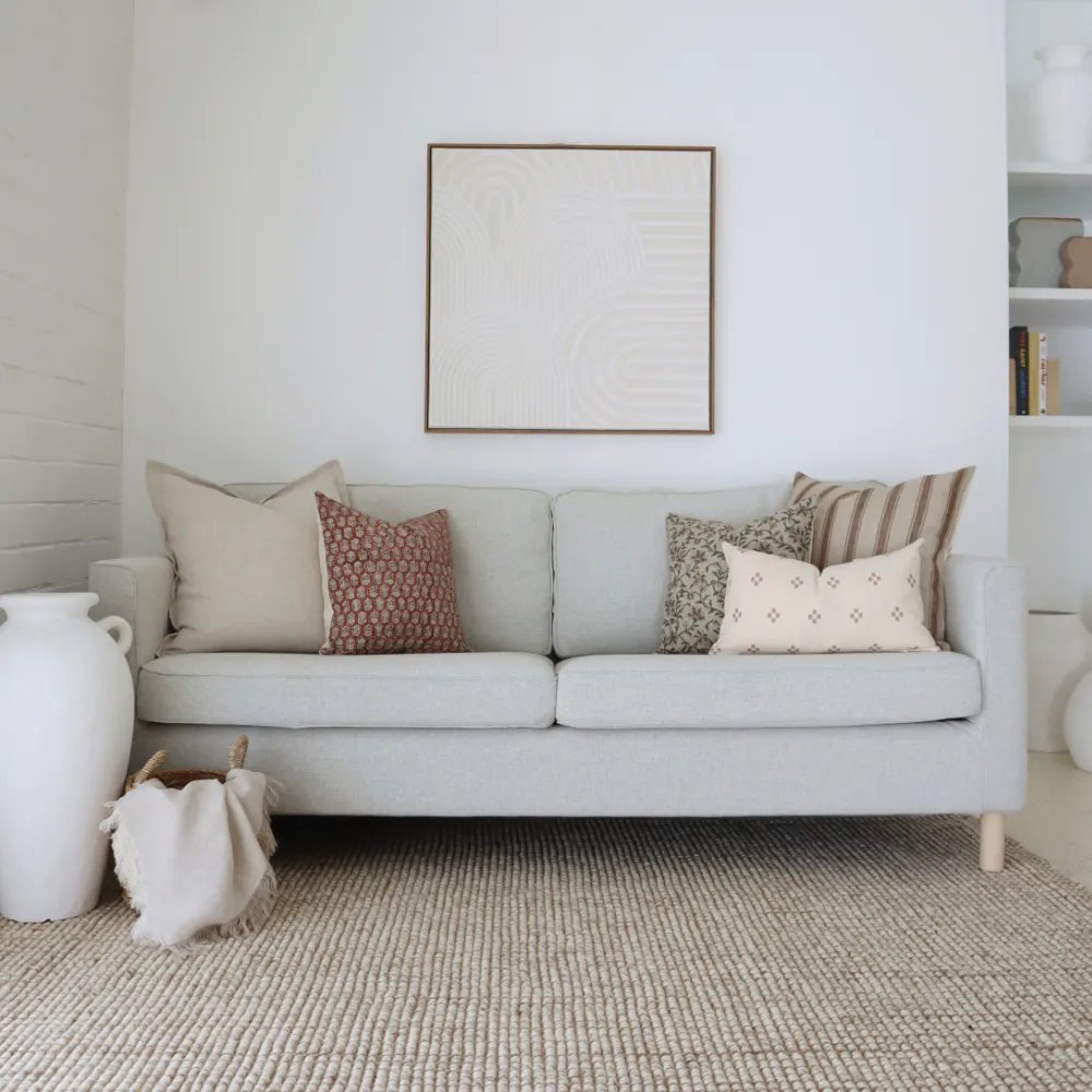 Five sofa cushions styled in a living room below artwork.